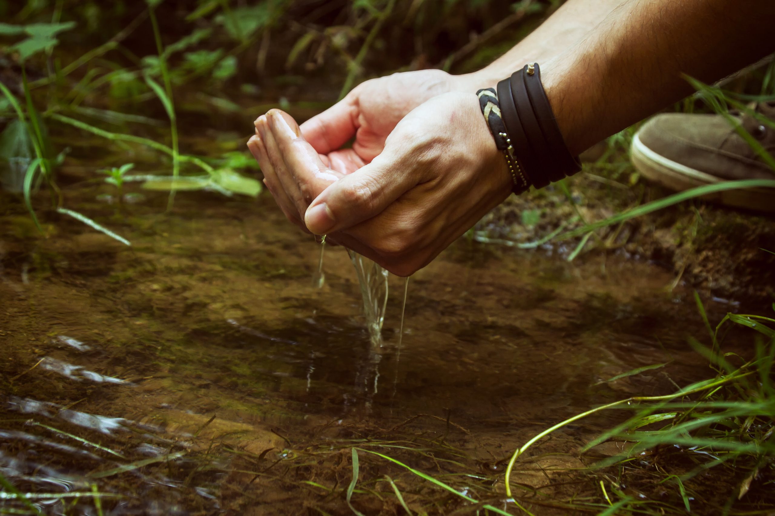 Man hand touching the cold water of a pond